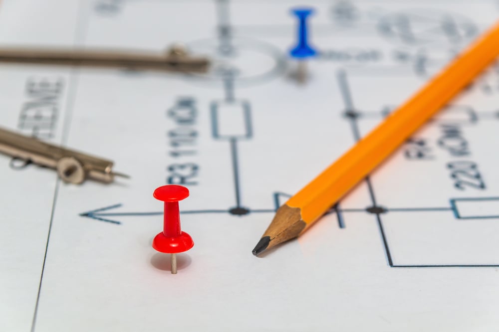 Red button and pencil on an electric diagram, working environment